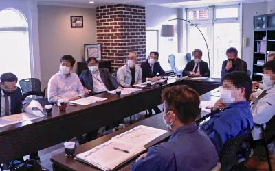 会議室に集まった工事業者の方々と工程会議の様子